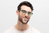 Mann trägt Juno Green, eine dicke, abgerundete, quadratische grüne Sonnenbrille mit gelben Gläsern
