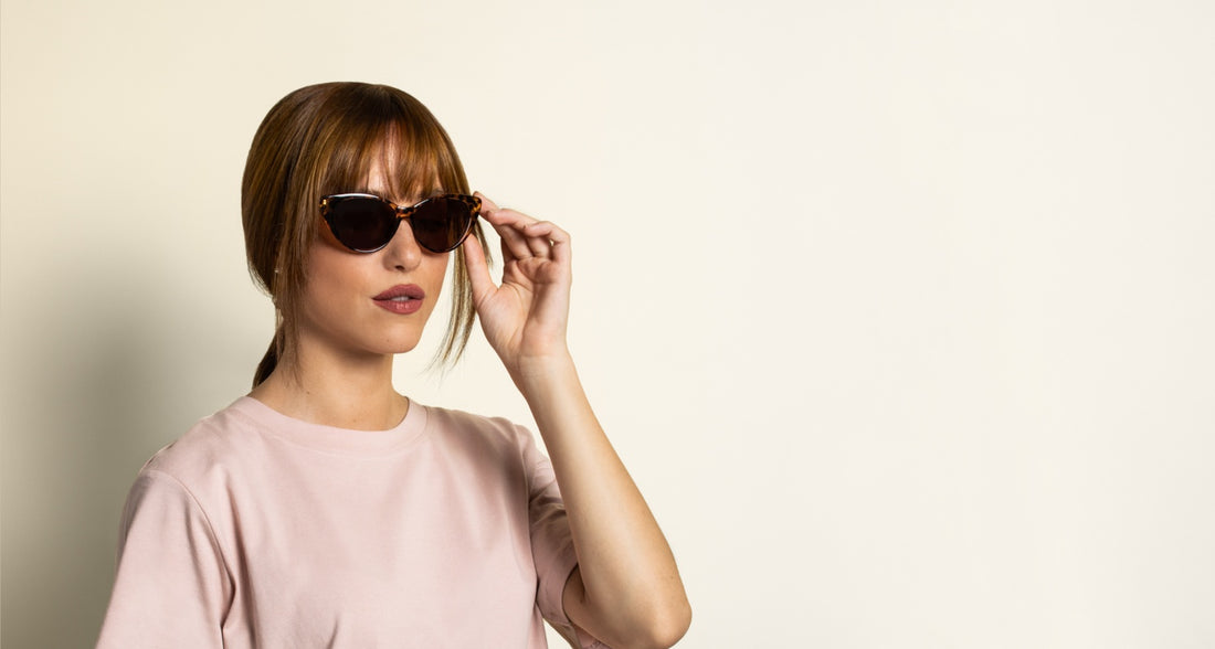 woman with oval face wearing cat-eye sunglasses on a pink background