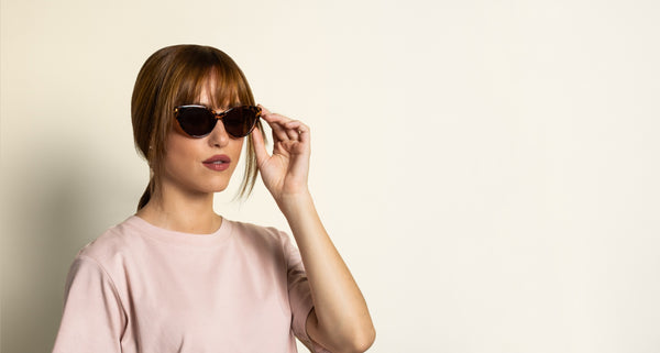 woman with oval face wearing cat-eye sunglasses on a pink background