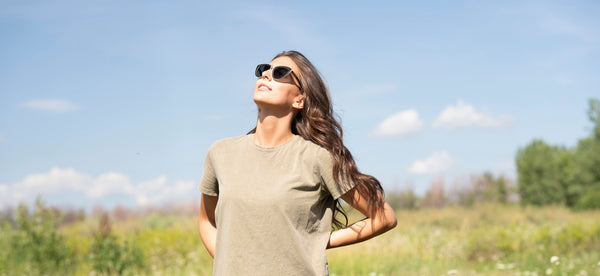 meisje met een zonnebril op dat naar de zon kijkt in een veld
