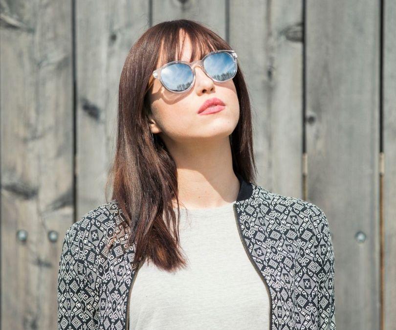 Femme portant Kraywoods Groove, lunettes de soleil rondes réfléchissantes avec monture transparente et bras en bois de zèbre avec protection UV à 100%, verres polarisés