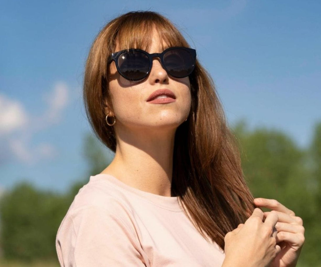 Femme portant des lunettes de soleil rondes Kraywoods Luxy avec bras en bois d'ébène avec protection UV à 100%, verres polarisés