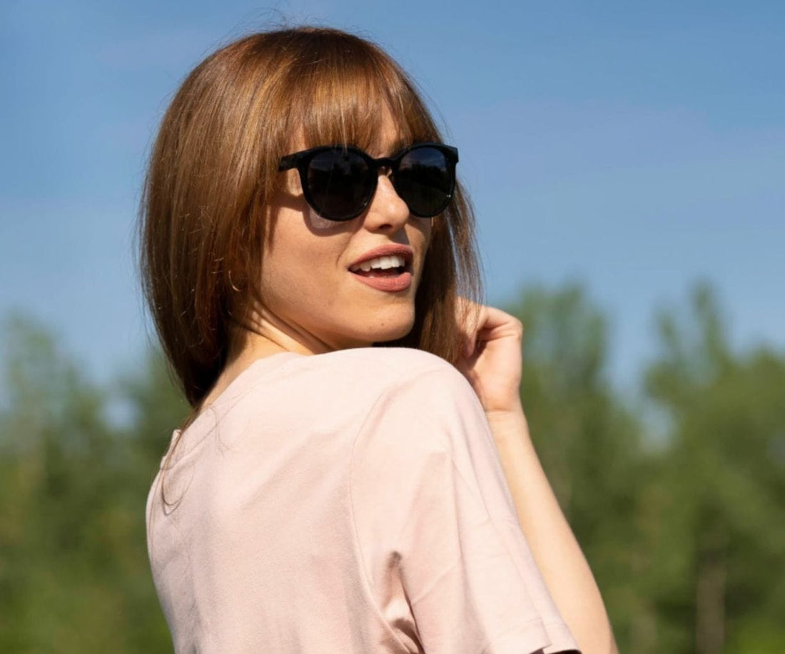 Femme portant des lunettes de soleil rondes Kraywoods Luxy avec bras en bois d'ébène avec protection UV à 100%, verres polarisés
