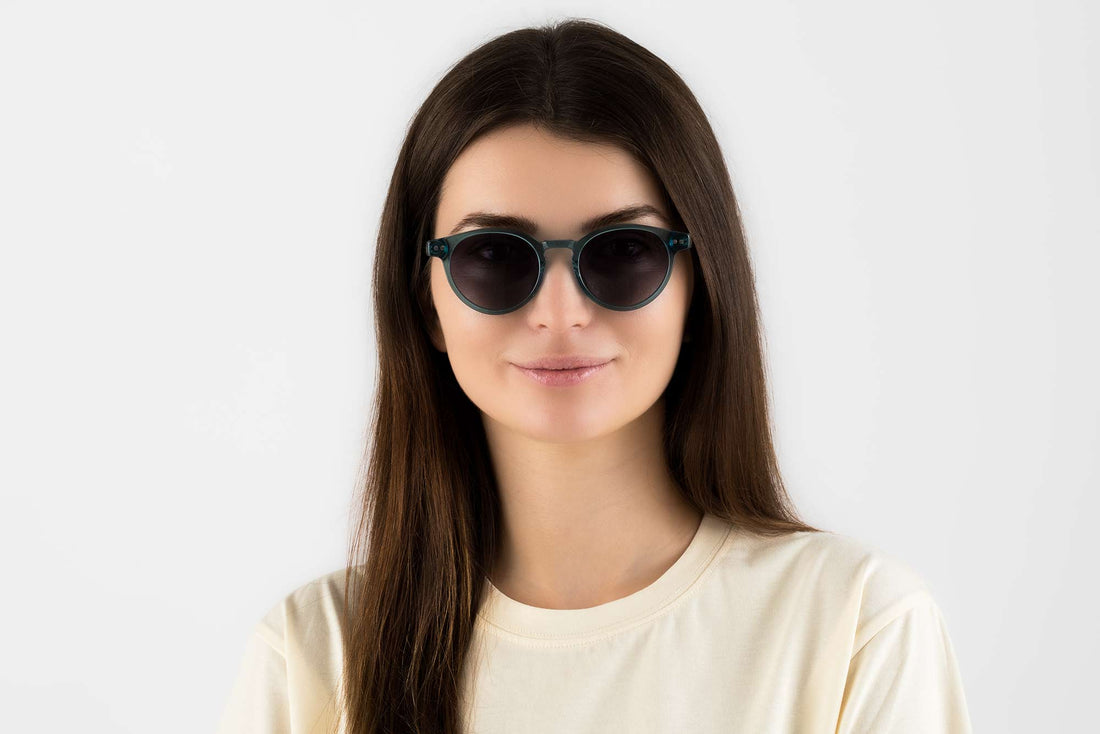 Mujer con gafas de sol redondas azules transparentes