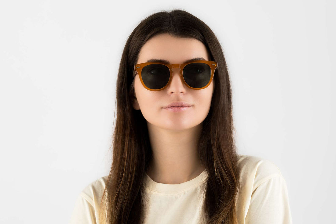 Mujer con gafas de sol redondas-cuadradas naranjas con lentes verdes polarizadas al atardecer