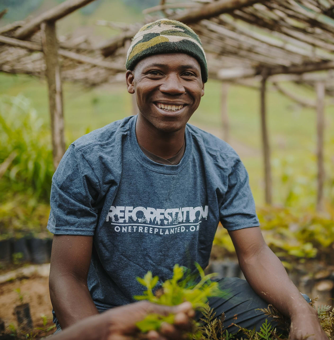 Un hombre sonriendo y plantando árboles