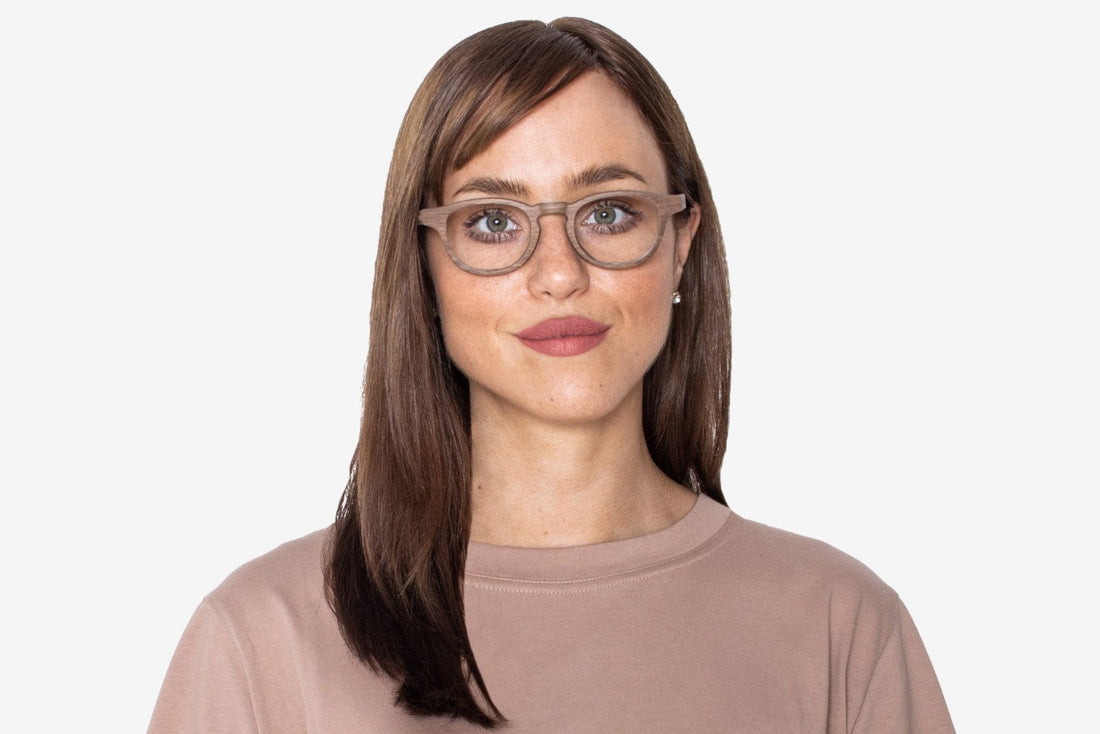 ハーモニー・ブラウンの角丸ウッドグラスをかけた女性