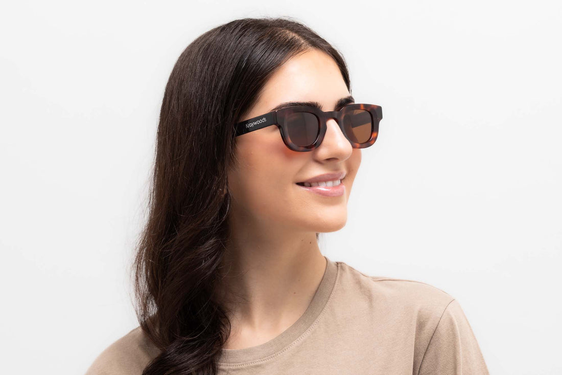 Kvinna bär Juno Brown Sunglasses, tjocka fyrkantiga solglasögon i sköldpaddsskal med brunt polariserat glas